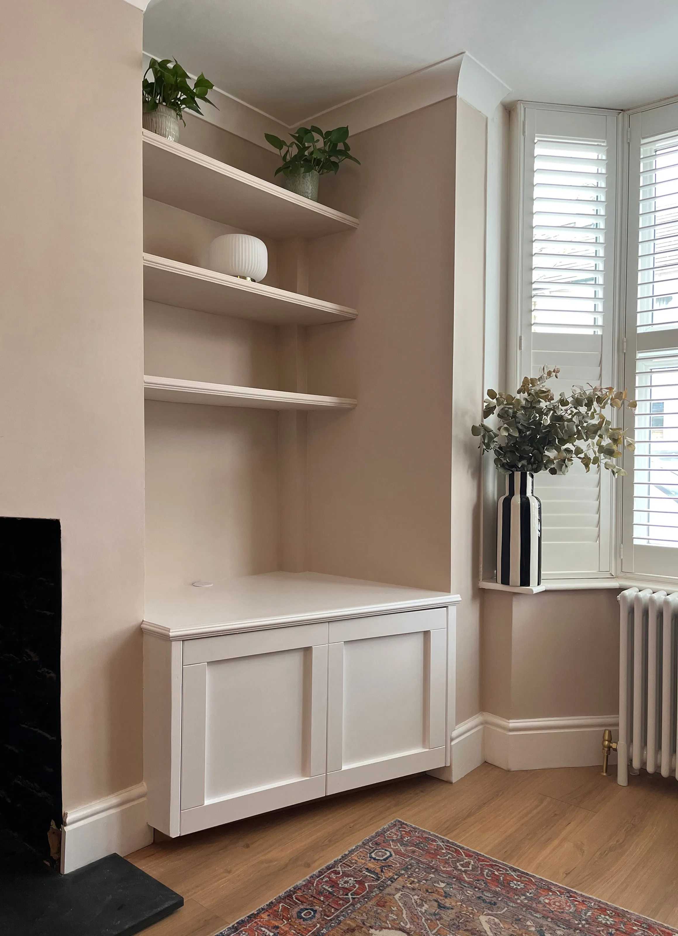 A right hand alcove unit showing three floating shelves, astragal moulding and an angled base unit with two shaker style doors