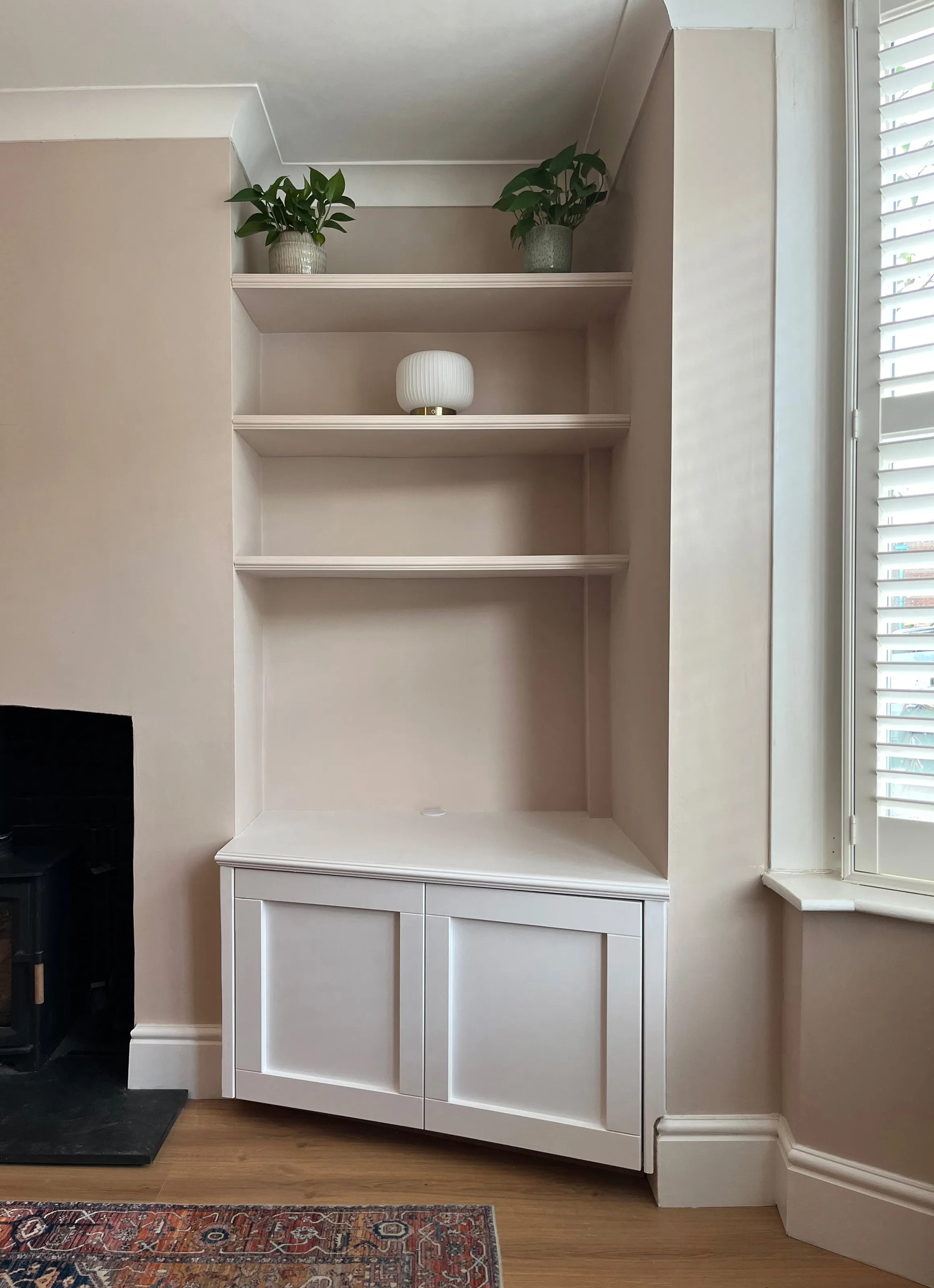 Front view of a right hand alcove unit showing three floating shelves and an angled bottom unit with shaker style doors