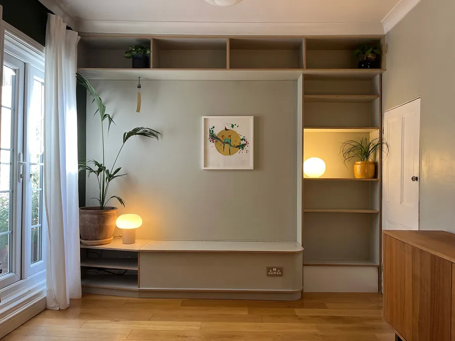 Full view of a modern bespoke dining or living room wall unit with banquette storage bench and integrated bookcase