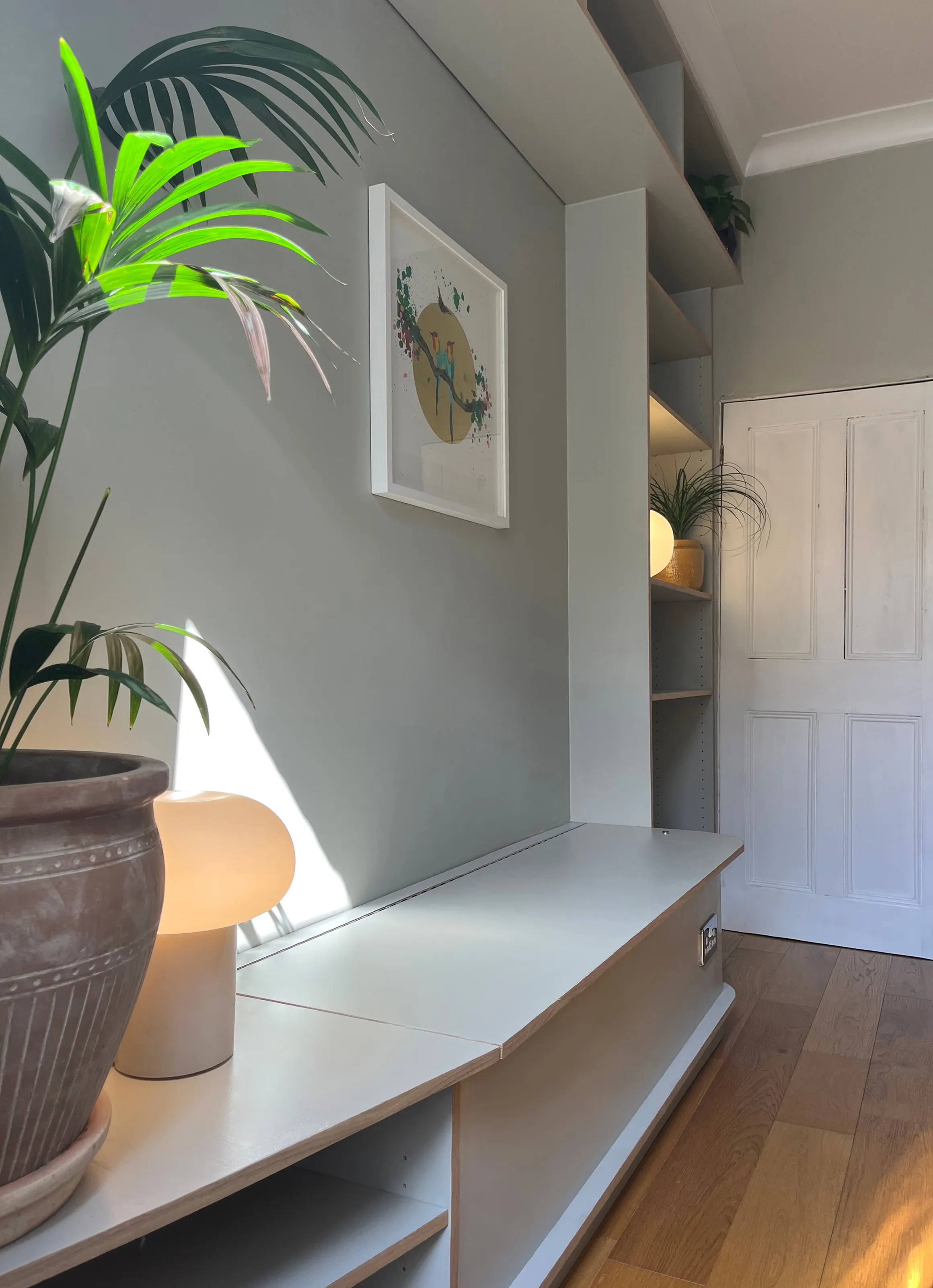 Angled perspective of a custom plywood bench seat with built-in storage and illuminated shelving unit