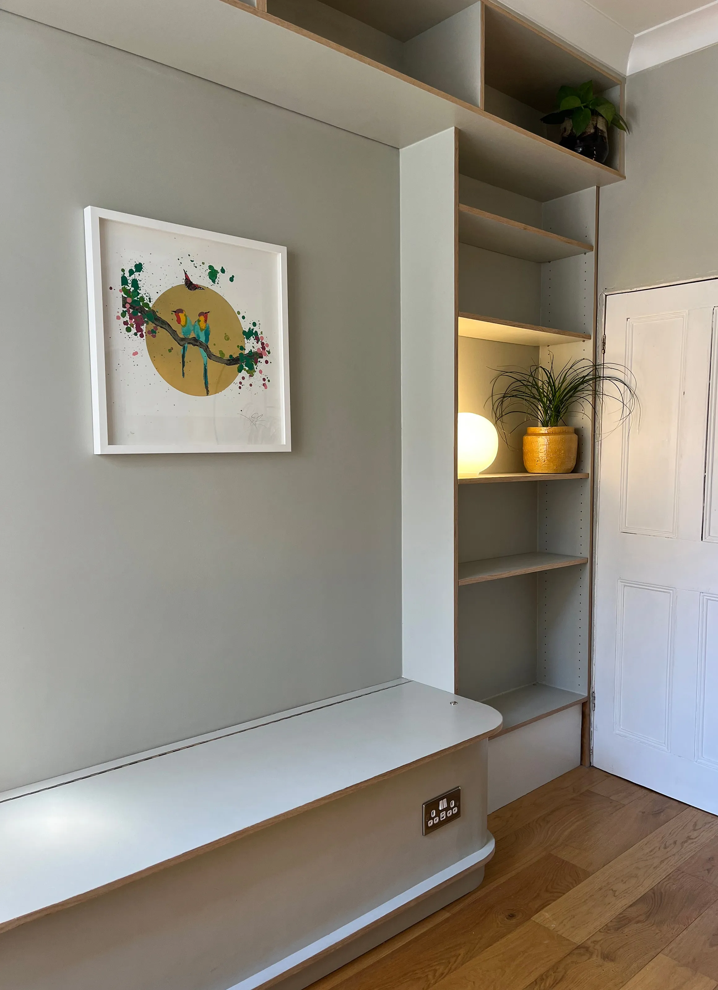 Side angle of modern custom joinery featuring a low storage bench and vertical floor-to-ceiling shelving