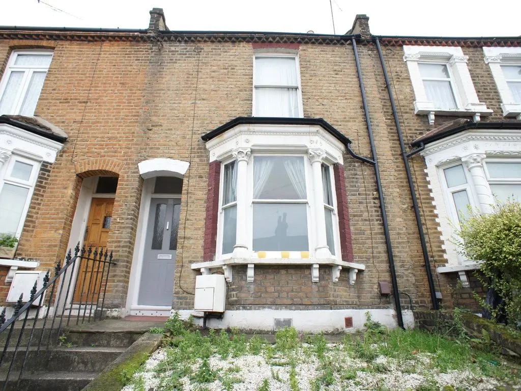 Victorian terrace house front garden before renovation featuring overgrown weeds and dated gravel, and uneven old steps