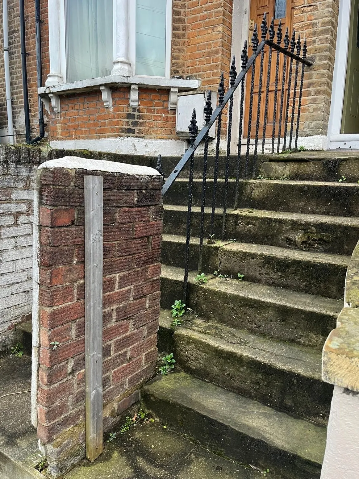 Old weathered concrete steps and unrendered brick retaining wall before front garden landscaping makeover