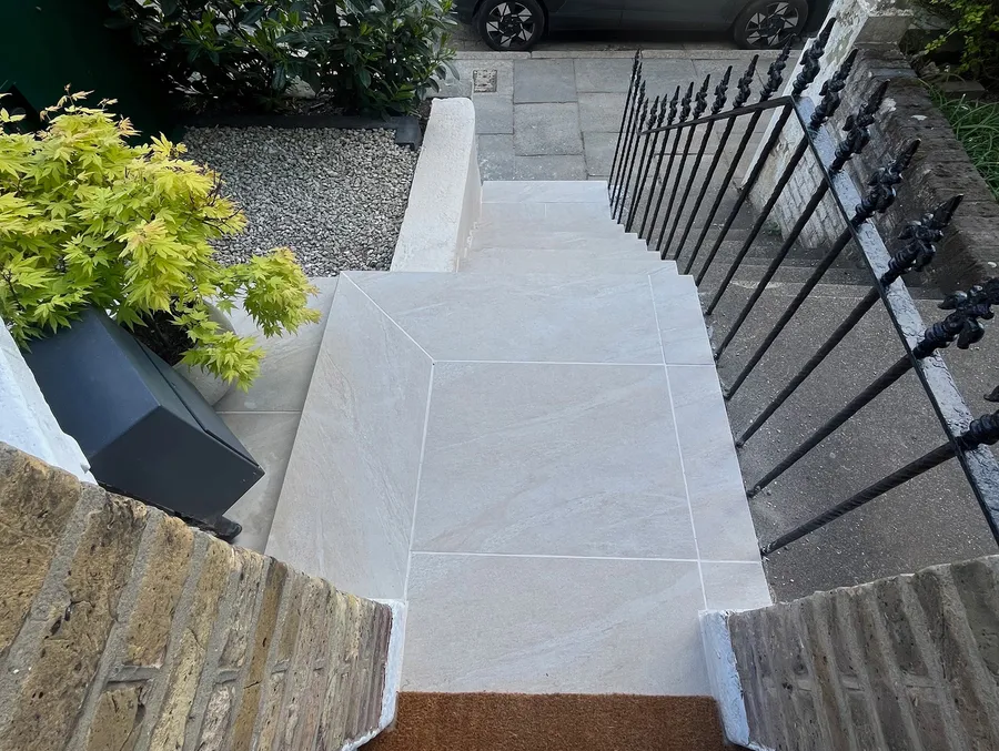 Top-down view of light beige outdoor porcelain steps leading down to a Victorian terraced house entrance