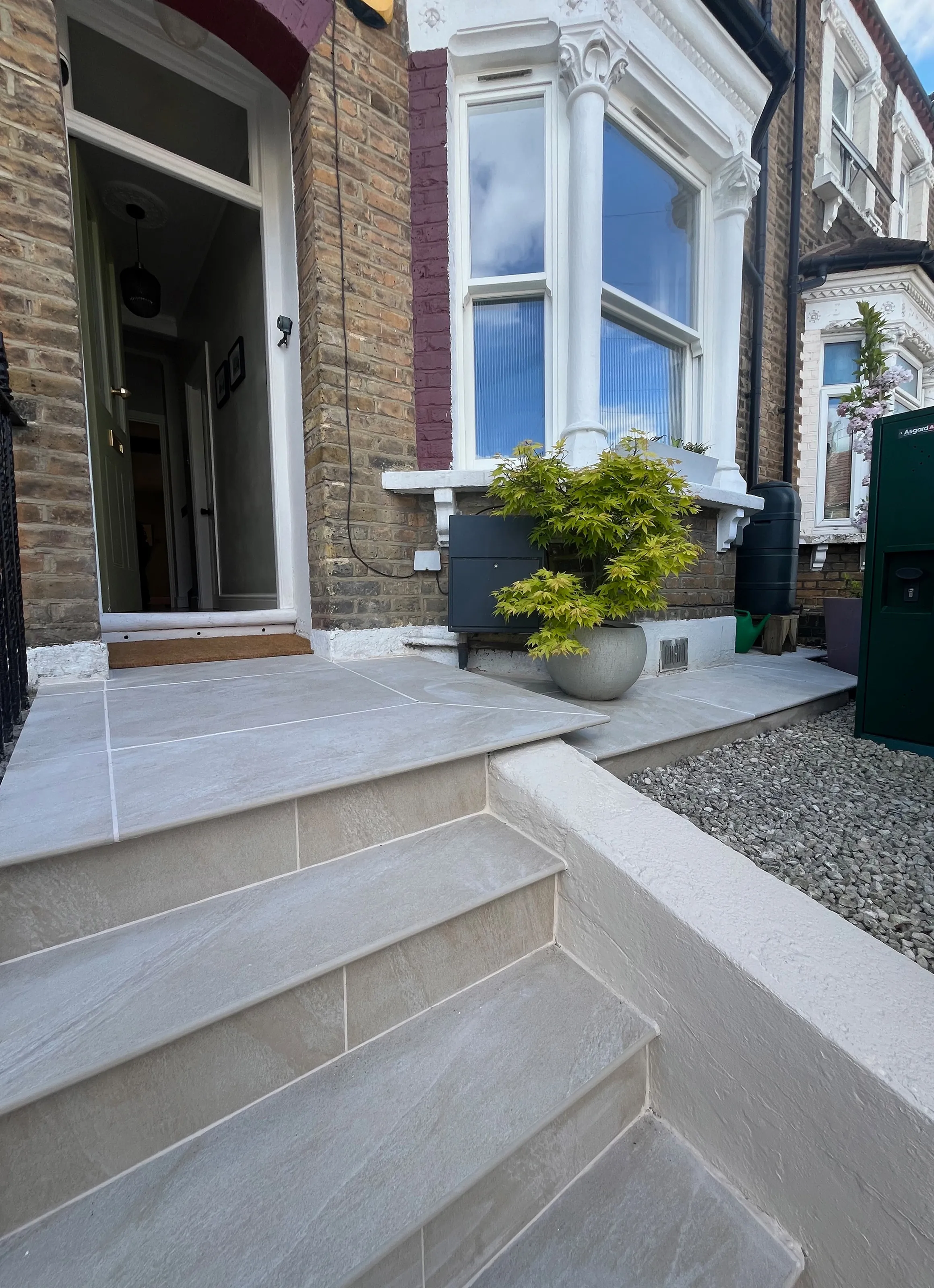 Renovated Victorian terrace front entrance with new light grey stone steps and smooth rendered retaining wall