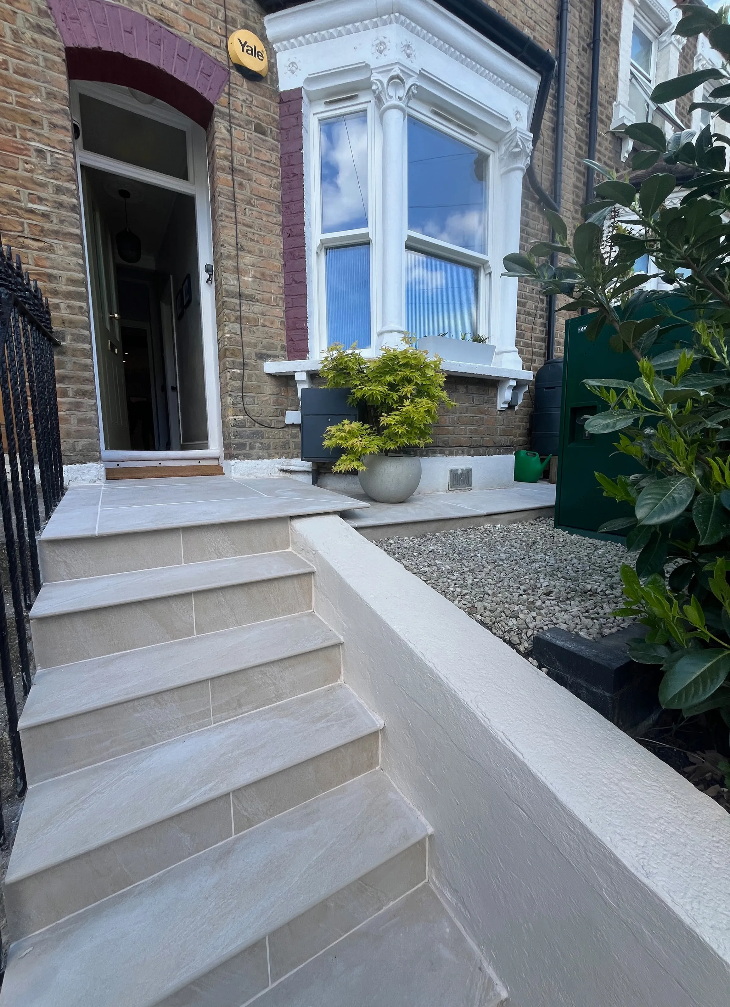 Low-angle view of custom outdoor tiled front steps leading to a brick Victorian terrace home showing a disguised green bike box