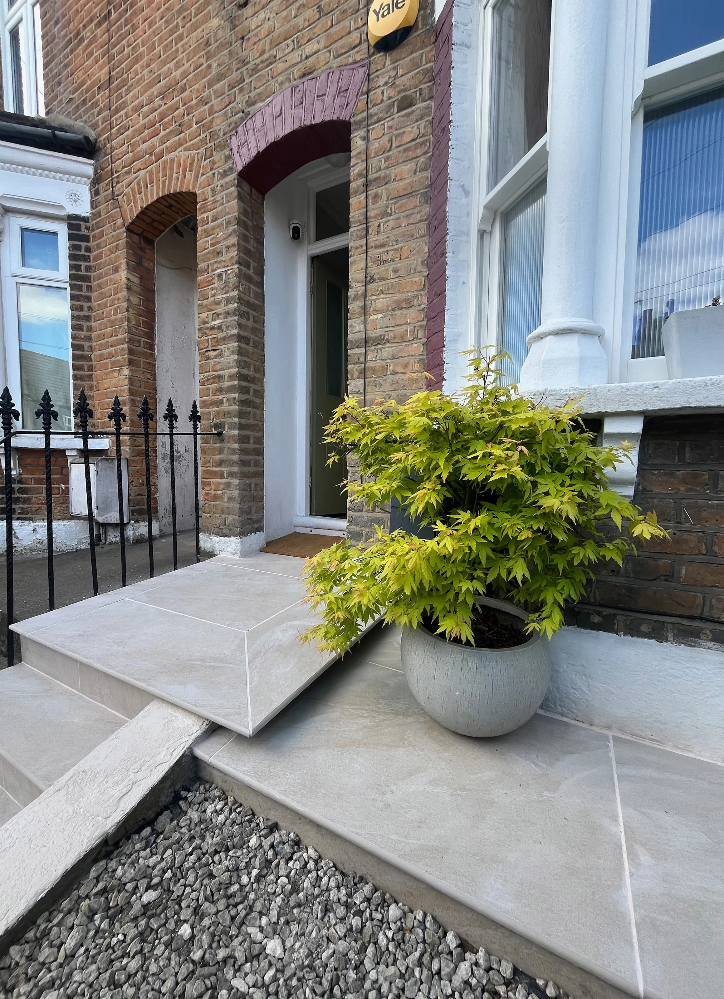 Close-up of newly paved front doorstep featuring potted Acer tree, gravel garden border, and Victorian brickwork