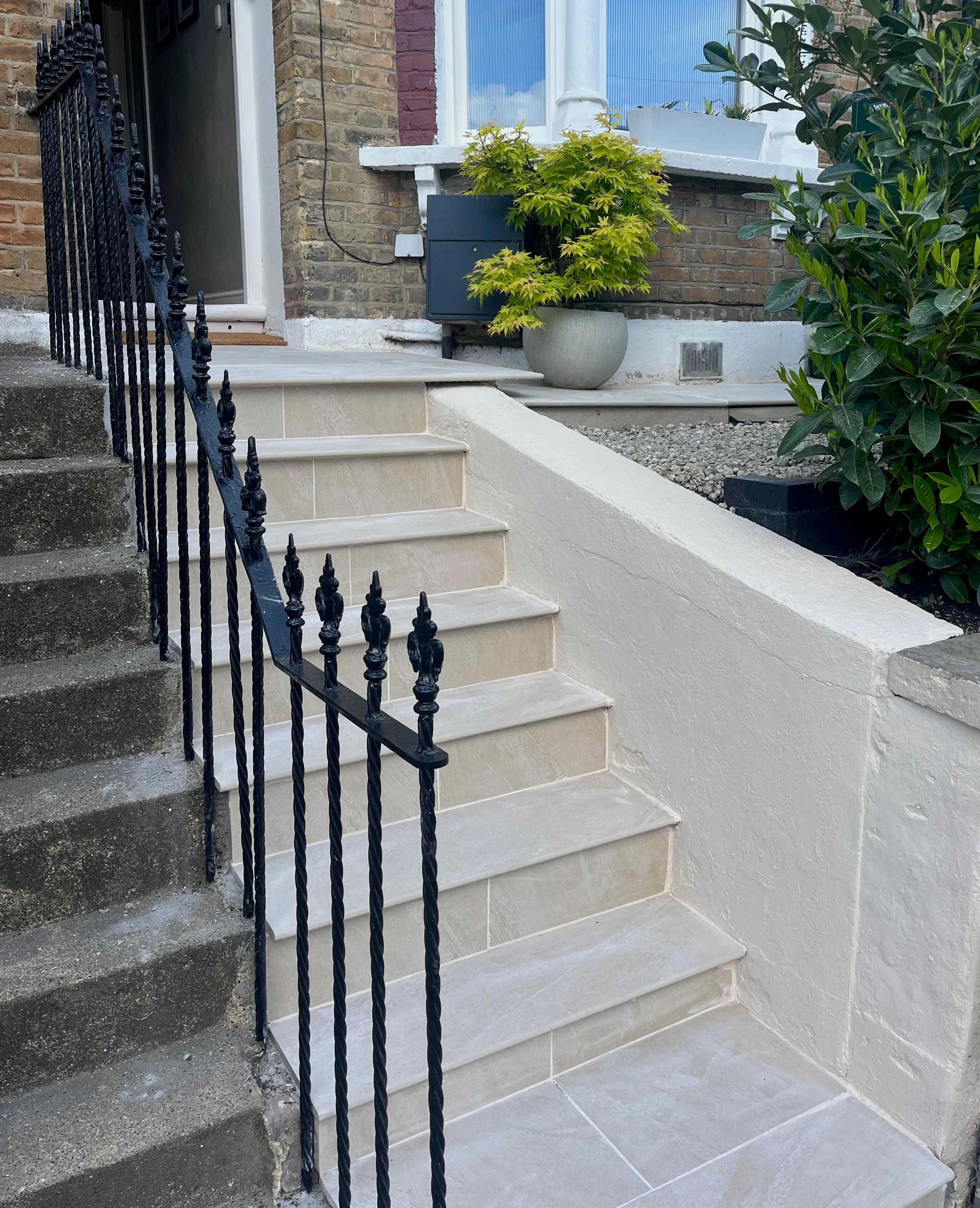 Front garden renovation showcasing new light grey stone steps, new wrought iron handrail, and rendered boundary wall