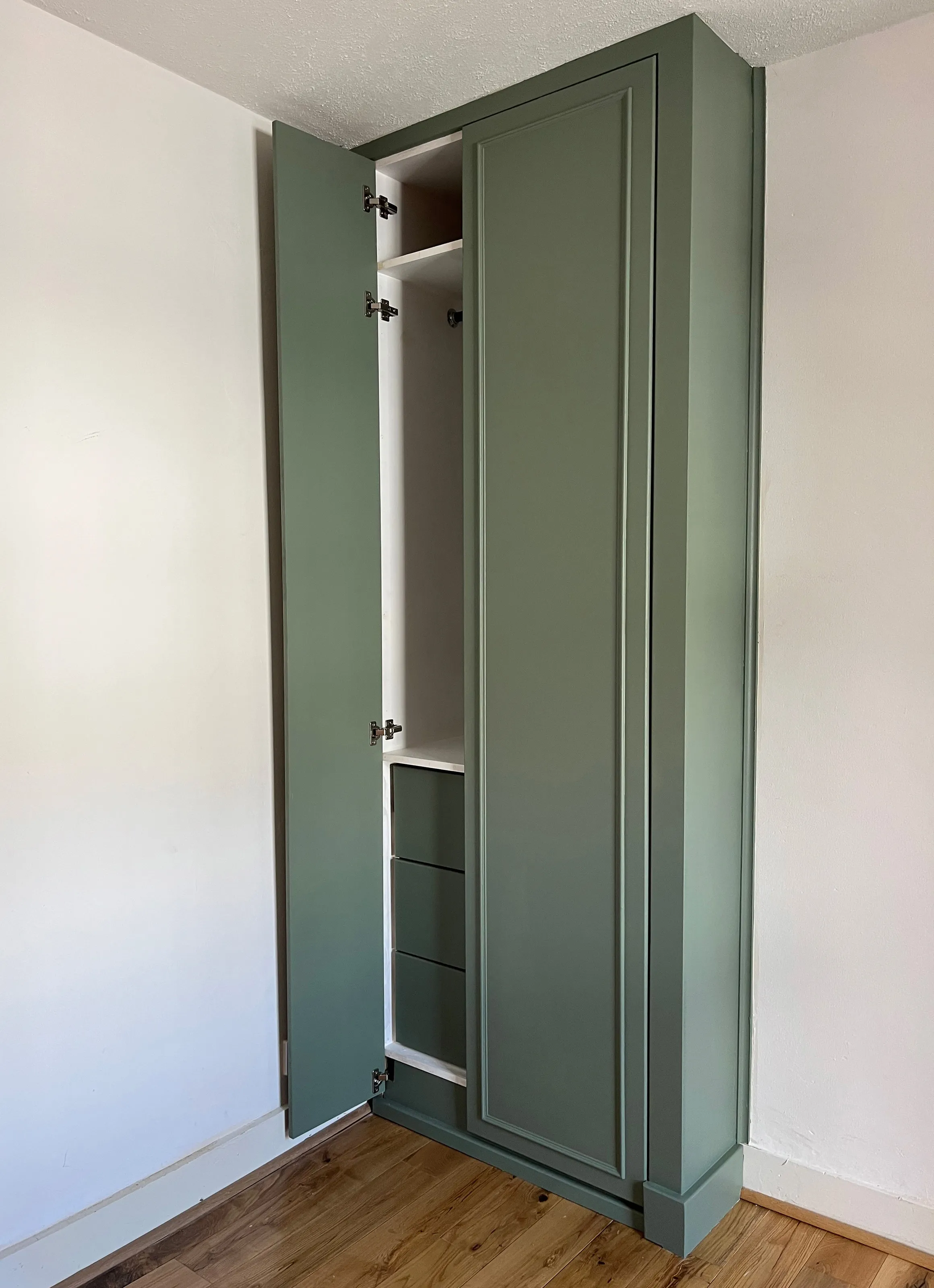 a view of the left hand wardrobe with a single smaller door open and the larger door closed